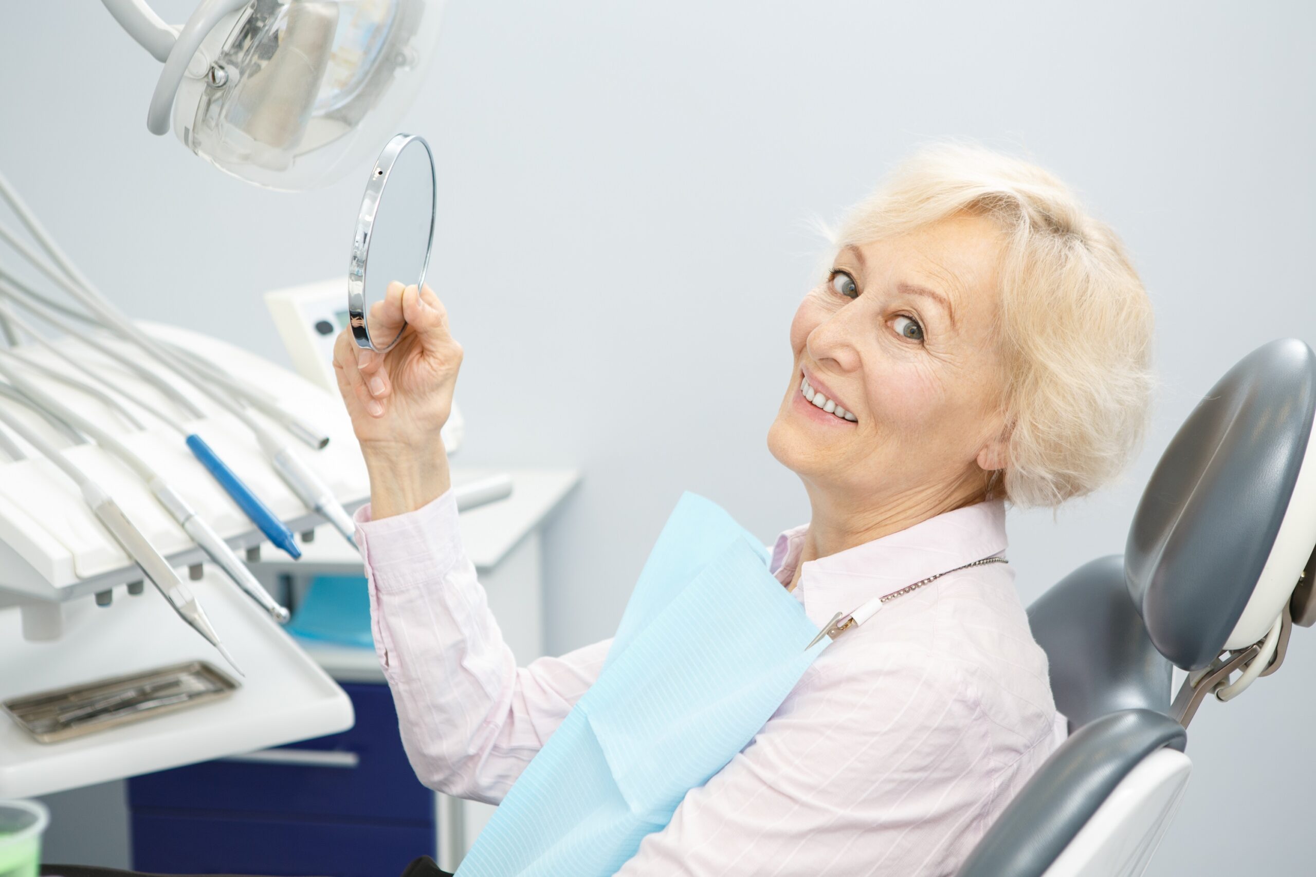 elderly woman sitting in a dentist chair and smiling