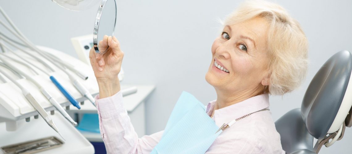 elderly woman sitting in a dentist chair and smiling